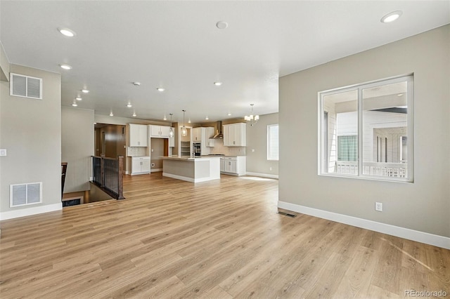 unfurnished living room featuring visible vents, baseboards, light wood finished floors, and recessed lighting