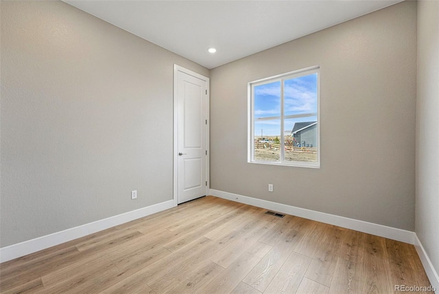 spare room featuring light wood-type flooring, baseboards, visible vents, and recessed lighting