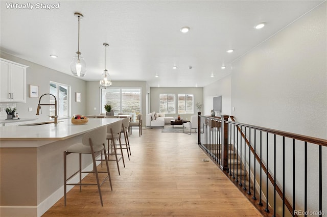 17196 W 92nd Loop, Arvada, CO 80007 - kitchen featuring a sink, white cabinets, light wood finished floors, pendant lighting, and light countertops