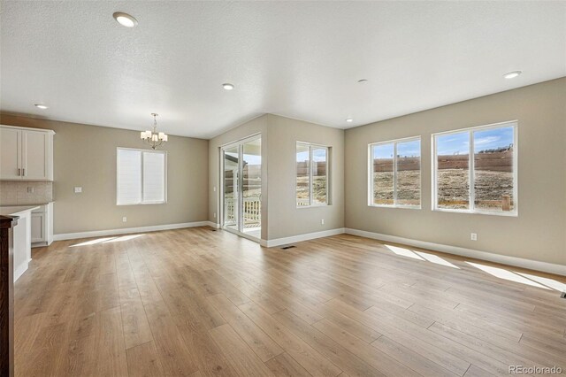 17196 W 92nd Loop, Arvada, CO 80007 - unfurnished living room with a chandelier, baseboards, healthy amount of natural light, and recessed lighting