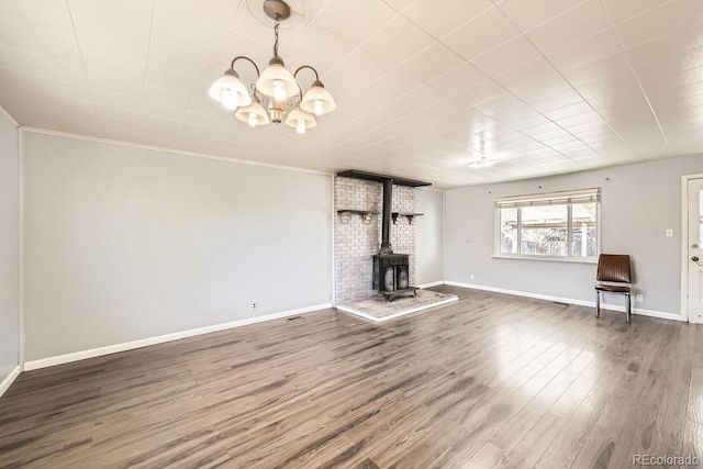 unfurnished living room featuring dark wood-type flooring, a chandelier, and a wood stove