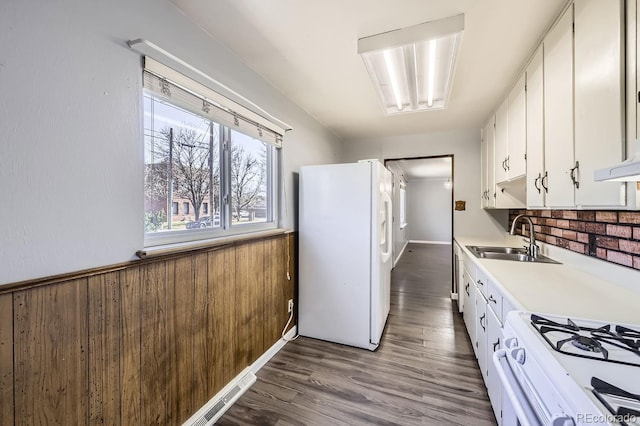 kitchen with sink, white appliances, hardwood / wood-style floors, and white cabinets