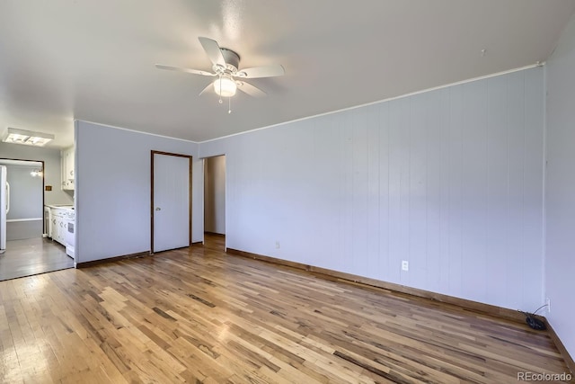 unfurnished bedroom with ceiling fan, wooden walls, ensuite bath, and light hardwood / wood-style floors