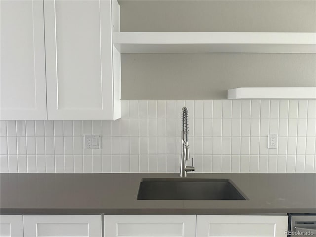 kitchen with dark countertops, white cabinetry, and a sink