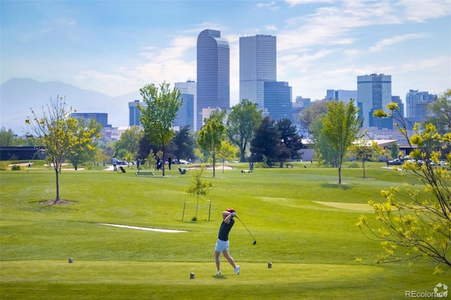 view of home's community with view of golf course, a yard, and a view of city