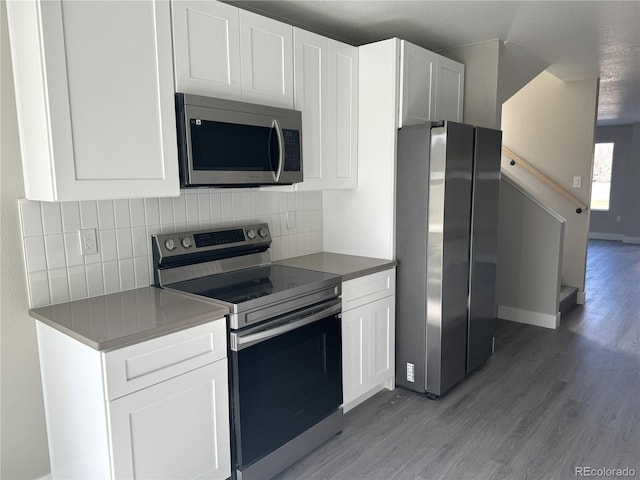kitchen featuring light wood finished floors, stainless steel appliances, white cabinets, and tasteful backsplash