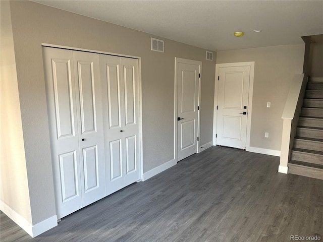 unfurnished bedroom with dark wood-style flooring, baseboards, a closet, and visible vents