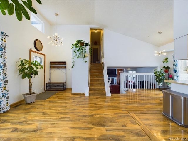 unfurnished living room featuring hardwood / wood-style flooring, lofted ceiling, and a chandelier