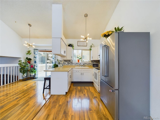 kitchen featuring a kitchen bar, high end refrigerator, decorative light fixtures, a chandelier, and kitchen peninsula