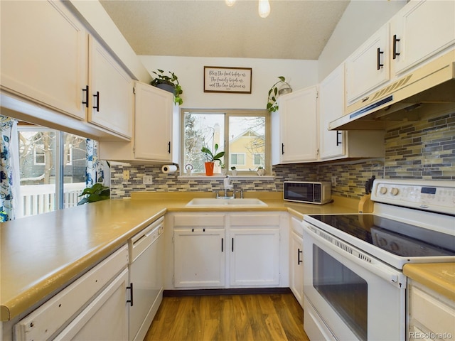 kitchen featuring tasteful backsplash, white cabinetry, sink, and white appliances