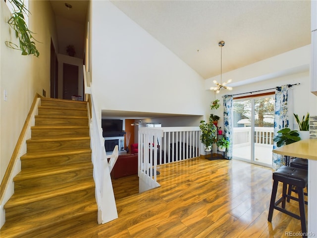 stairway featuring hardwood / wood-style flooring, high vaulted ceiling, and a chandelier