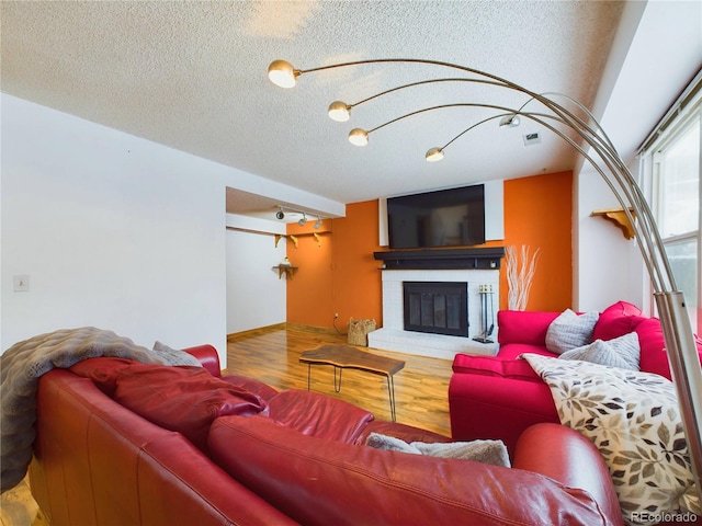 living room featuring wood-type flooring, a fireplace, and a textured ceiling