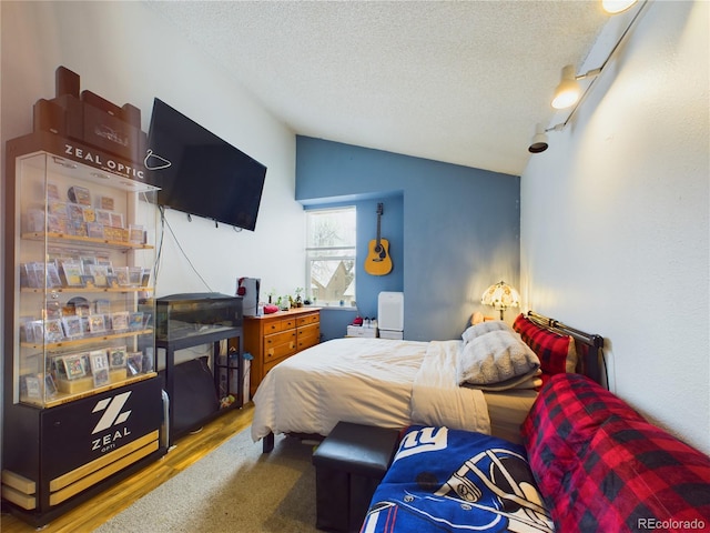 bedroom with hardwood / wood-style flooring, lofted ceiling, and a textured ceiling