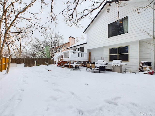 snow covered house with a wooden deck