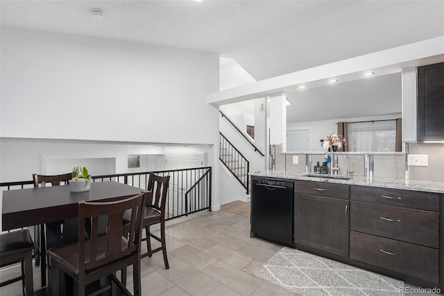 kitchen featuring dark brown cabinetry, dishwasher, light stone countertops, and a sink