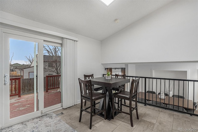 dining space with visible vents, a textured ceiling, and vaulted ceiling