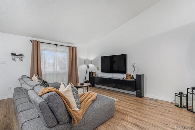 living room featuring visible vents, baseboards, light wood-style flooring, and vaulted ceiling