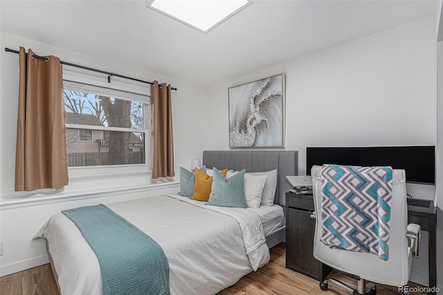 bedroom with wood finished floors, baseboards, and a textured ceiling