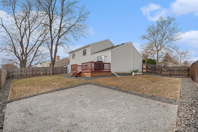 back of house featuring a fenced backyard, a lawn, and a deck