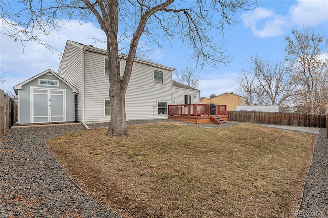 rear view of house with a storage unit, an outbuilding, a fenced backyard, a yard, and a wooden deck