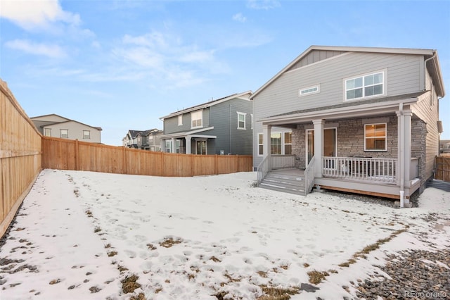 snow covered rear of property with a porch