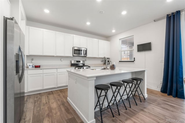 kitchen with appliances with stainless steel finishes, sink, a breakfast bar, and a kitchen island with sink