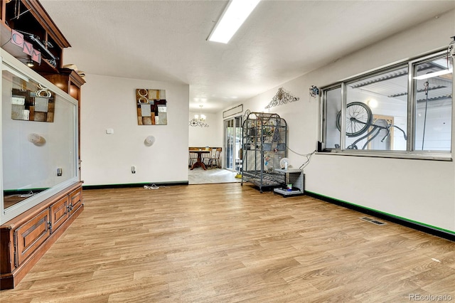 exercise area featuring light hardwood / wood-style floors and a notable chandelier