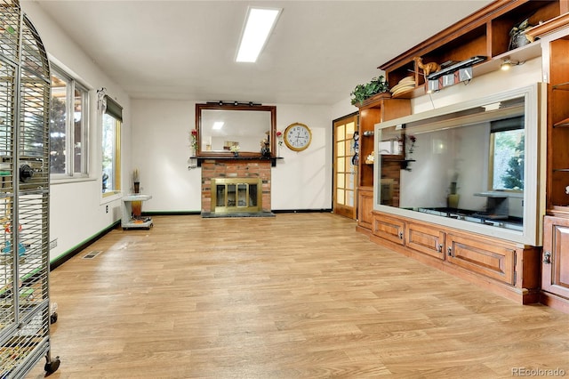 unfurnished living room featuring light hardwood / wood-style floors, a healthy amount of sunlight, and a fireplace