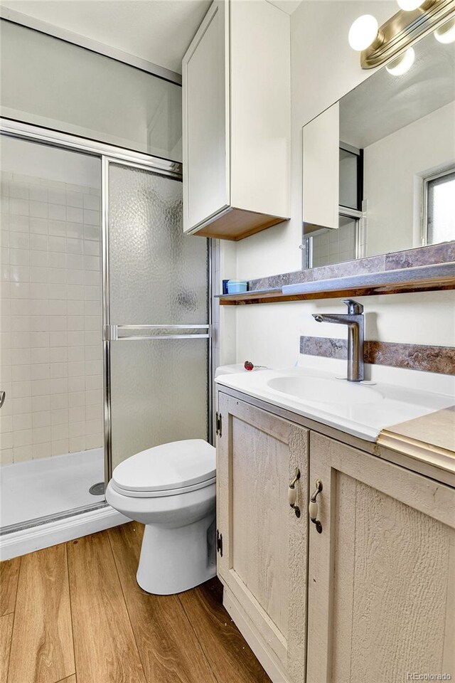 bathroom with vanity, toilet, wood-type flooring, and a shower with door