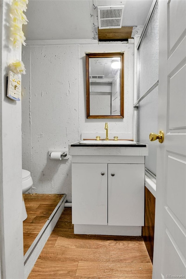 bathroom with vanity, toilet, hardwood / wood-style flooring, and walk in shower