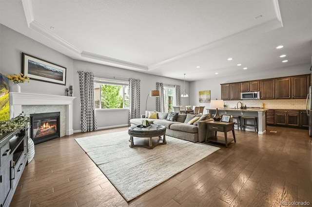 16256 Ute Peak Way, Broomfield, CO 80023 - living area with a tray ceiling, recessed lighting, dark wood-style floors, and a tiled fireplace