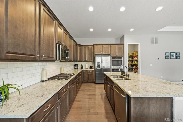 16256 Ute Peak Way, Broomfield, CO 80023 - kitchen with stainless steel appliances, recessed lighting, decorative backsplash, wood finished floors, and a kitchen island with sink