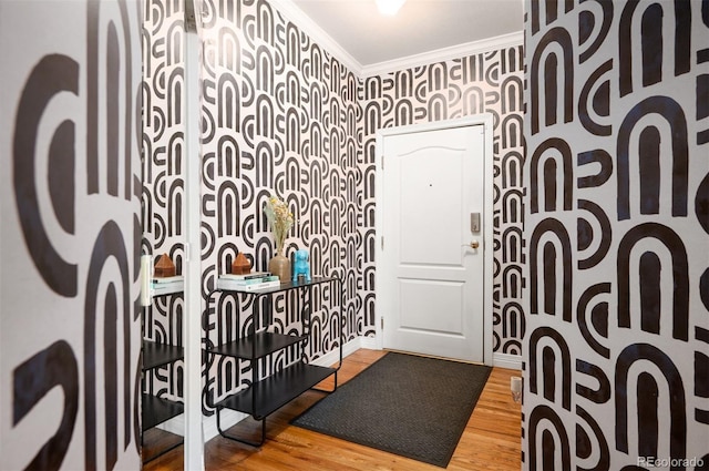 interior space featuring baseboards, wood finished floors, crown molding, and wallpapered walls