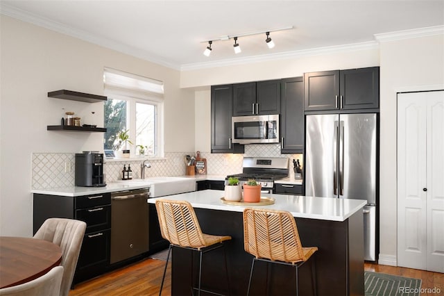 kitchen with a kitchen island, a kitchen bar, light countertops, appliances with stainless steel finishes, and wood finished floors