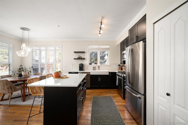 kitchen with a breakfast bar, crown molding, appliances with stainless steel finishes, and a center island