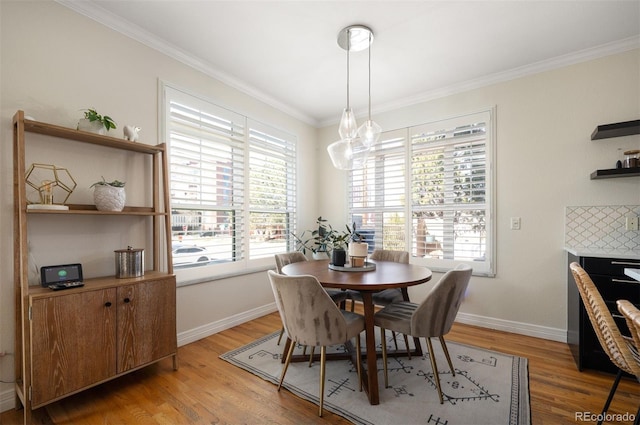 dining space with light wood-type flooring, crown molding, and baseboards