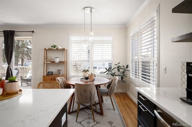 dining area featuring baseboards, crown molding, and light wood-style floors