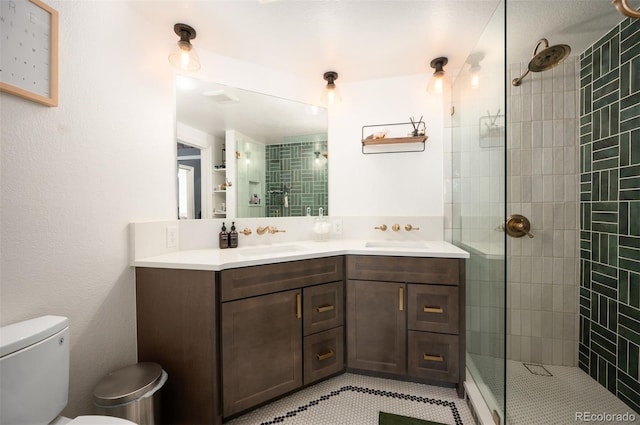 bathroom with a tile shower, toilet, and vanity