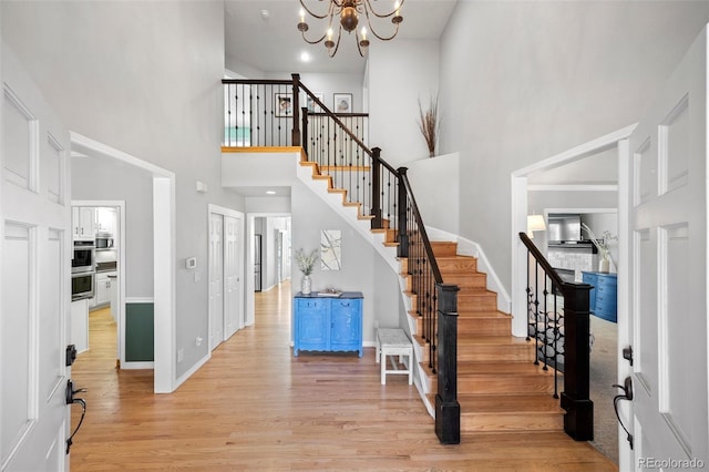 404 Yarrow Pl, Castle Pines, CO 80108 - entryway featuring a high ceiling, stairway, light wood-style floors, a chandelier, and baseboards