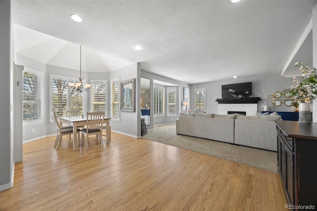 404 Yarrow Pl, Castle Pines, CO 80108 - living room with a textured ceiling, baseboards, light wood finished floors, a chandelier, and a brick fireplace