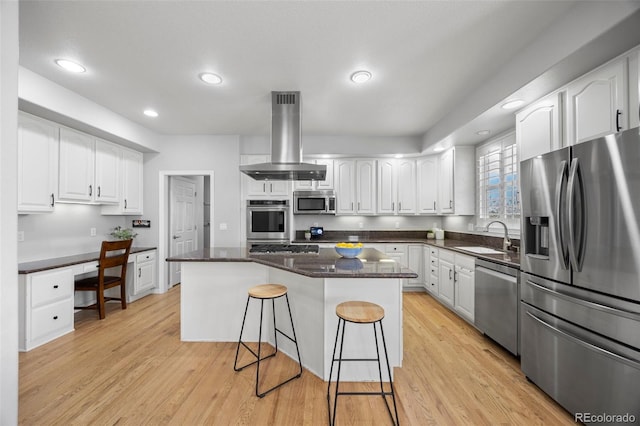 404 Yarrow Pl, Castle Pines, CO 80108 - kitchen featuring appliances with stainless steel finishes, island exhaust hood, a sink, a breakfast bar, and white cabinetry