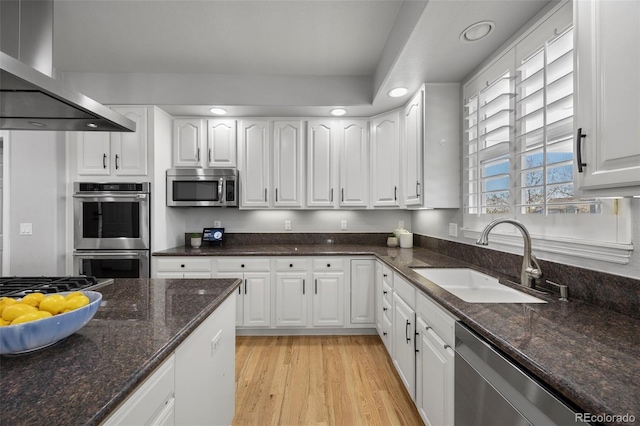 404 Yarrow Pl, Castle Pines, CO 80108 - kitchen with stainless steel appliances, a sink, wall chimney exhaust hood, white cabinets, and dark stone countertops