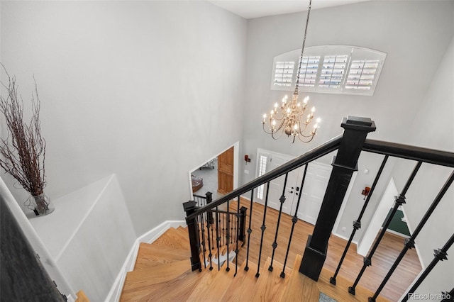 404 Yarrow Pl, Castle Pines, CO 80108 - stairs featuring wood finished floors, a chandelier, a high ceiling, and baseboards
