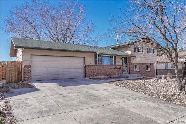 split level home featuring brick siding, concrete driveway, an attached garage, and fence