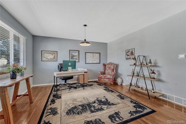 office area with wood finished floors, visible vents, and baseboards