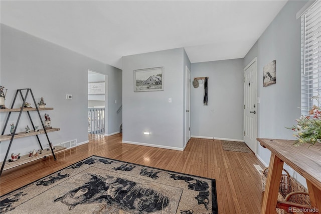 foyer entrance with visible vents, baseboards, and wood finished floors