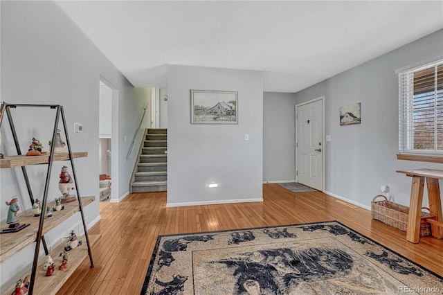 foyer entrance featuring stairway, light wood-type flooring, and baseboards