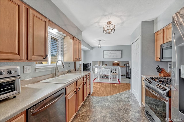 kitchen with a toaster, a sink, light countertops, appliances with stainless steel finishes, and a chandelier