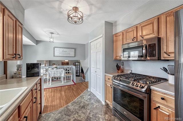 kitchen with brown cabinets, appliances with stainless steel finishes, light countertops, and a sink