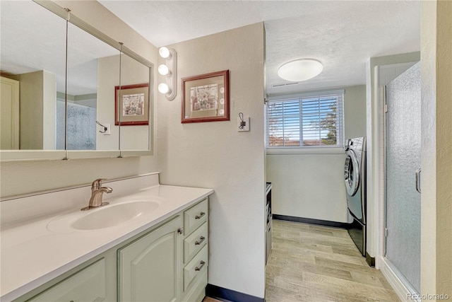 bathroom featuring vanity, wood finished floors, baseboards, washer / clothes dryer, and a textured ceiling